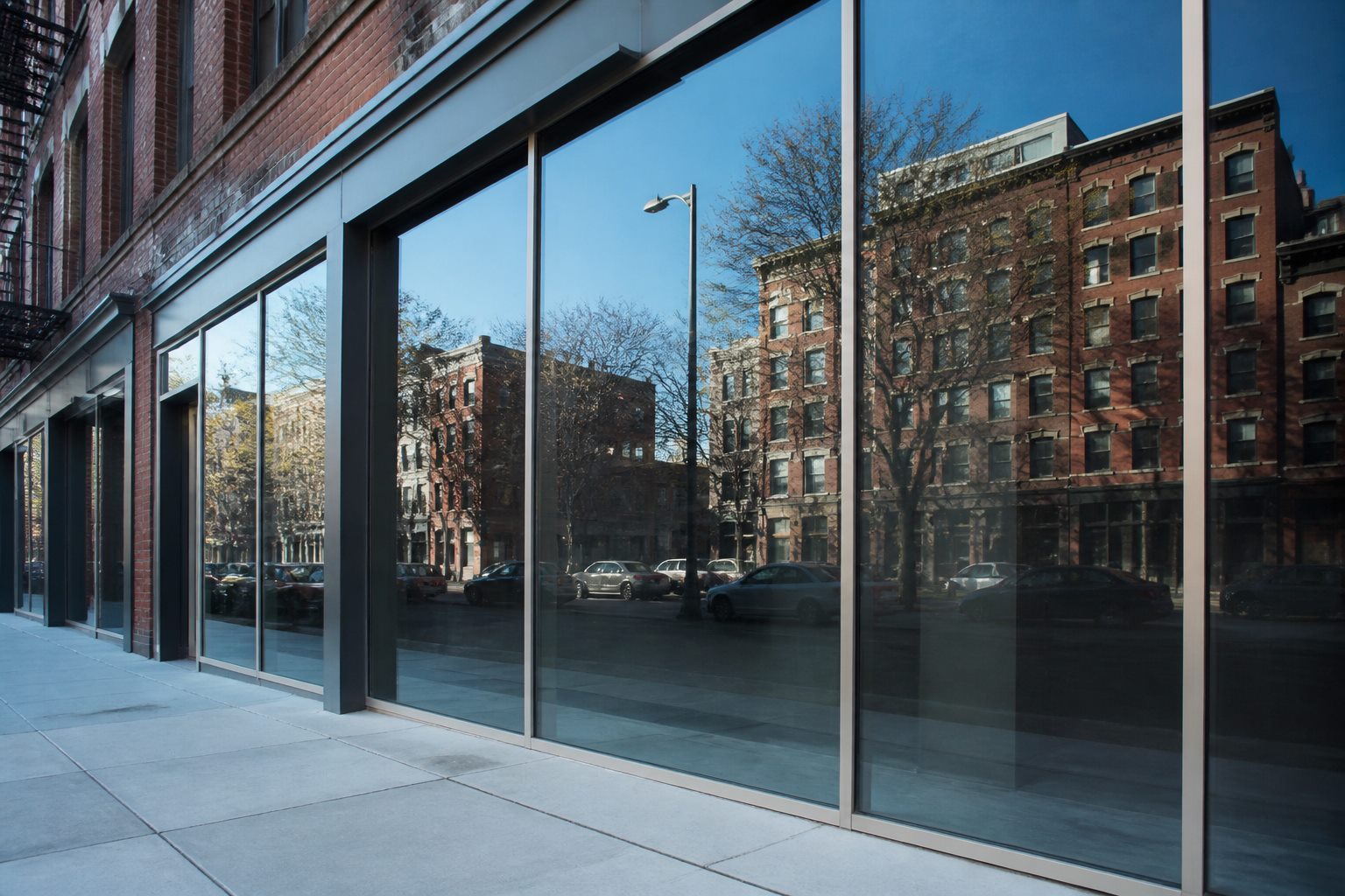 Brooklyn storefront glazed with floor-to-ceiling panes reflecting a clear blue sky